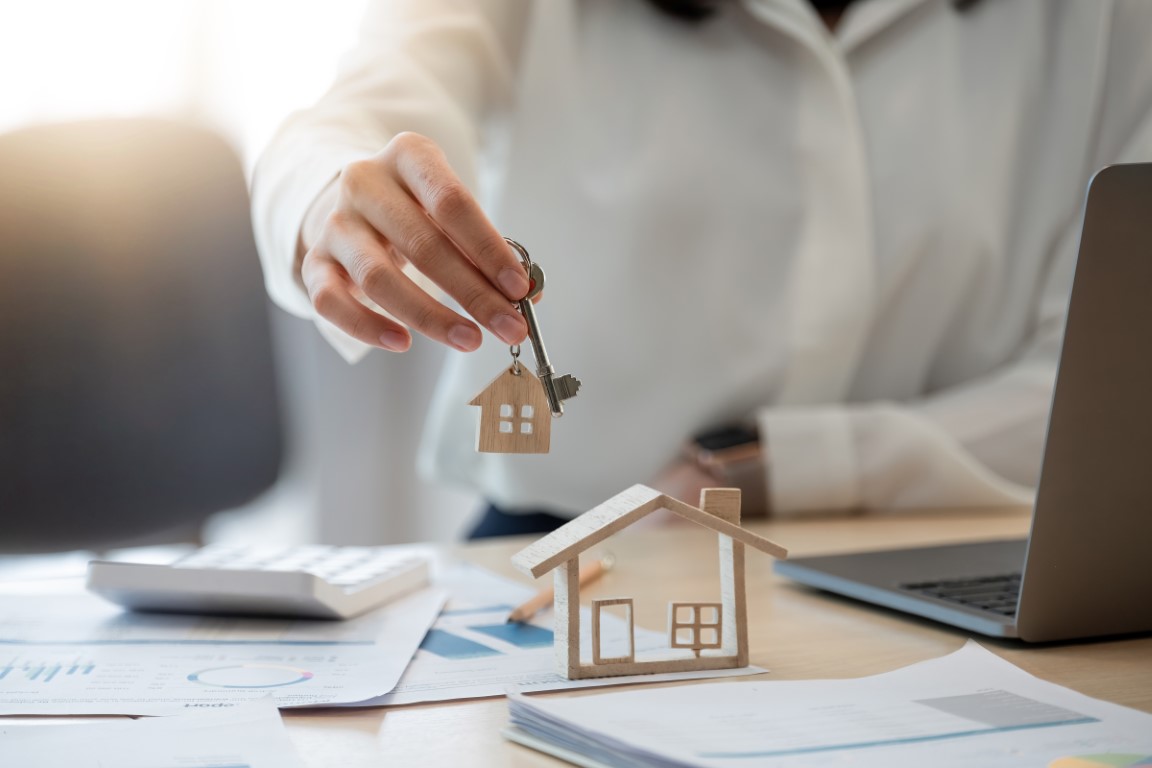 Female hand holding house key,real estate agent woman working ho Female hand holding house key,real estate agent woman working house loan at her office.